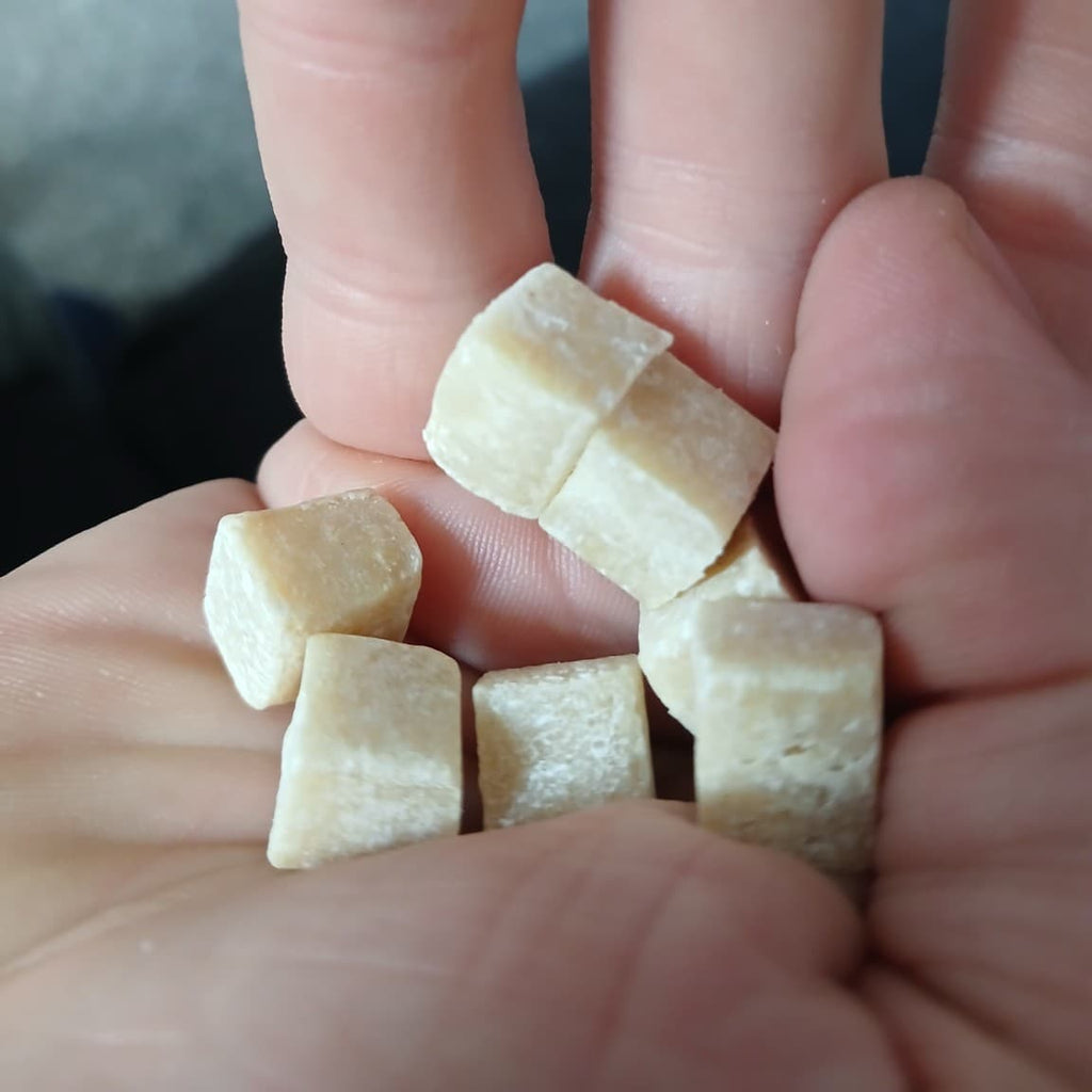 Small pieces of chewing gum held between fingers against a blurred background