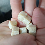 Small pieces of chewing gum held between fingers against a blurred background