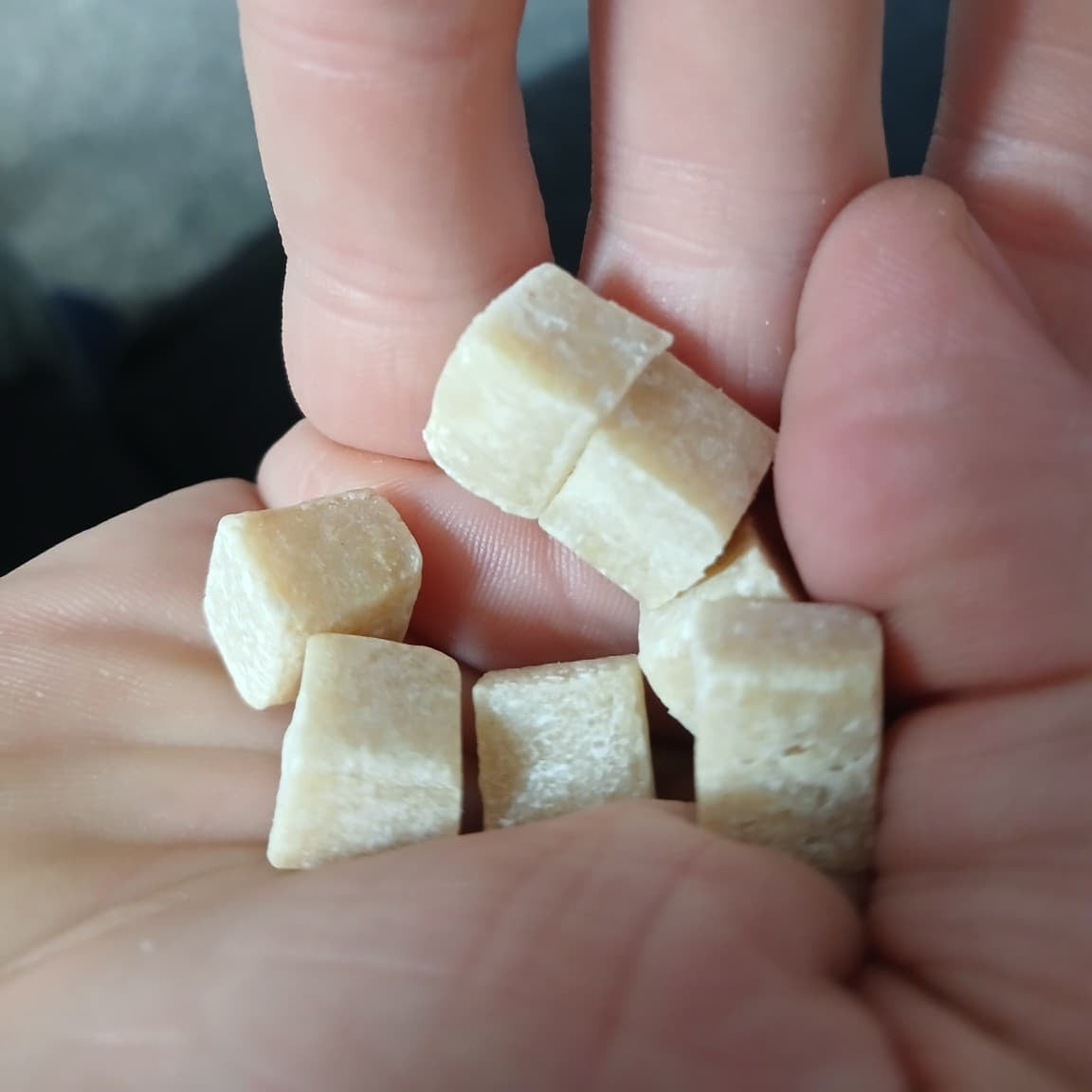 Small pieces of chewing gum held between fingers against a blurred background