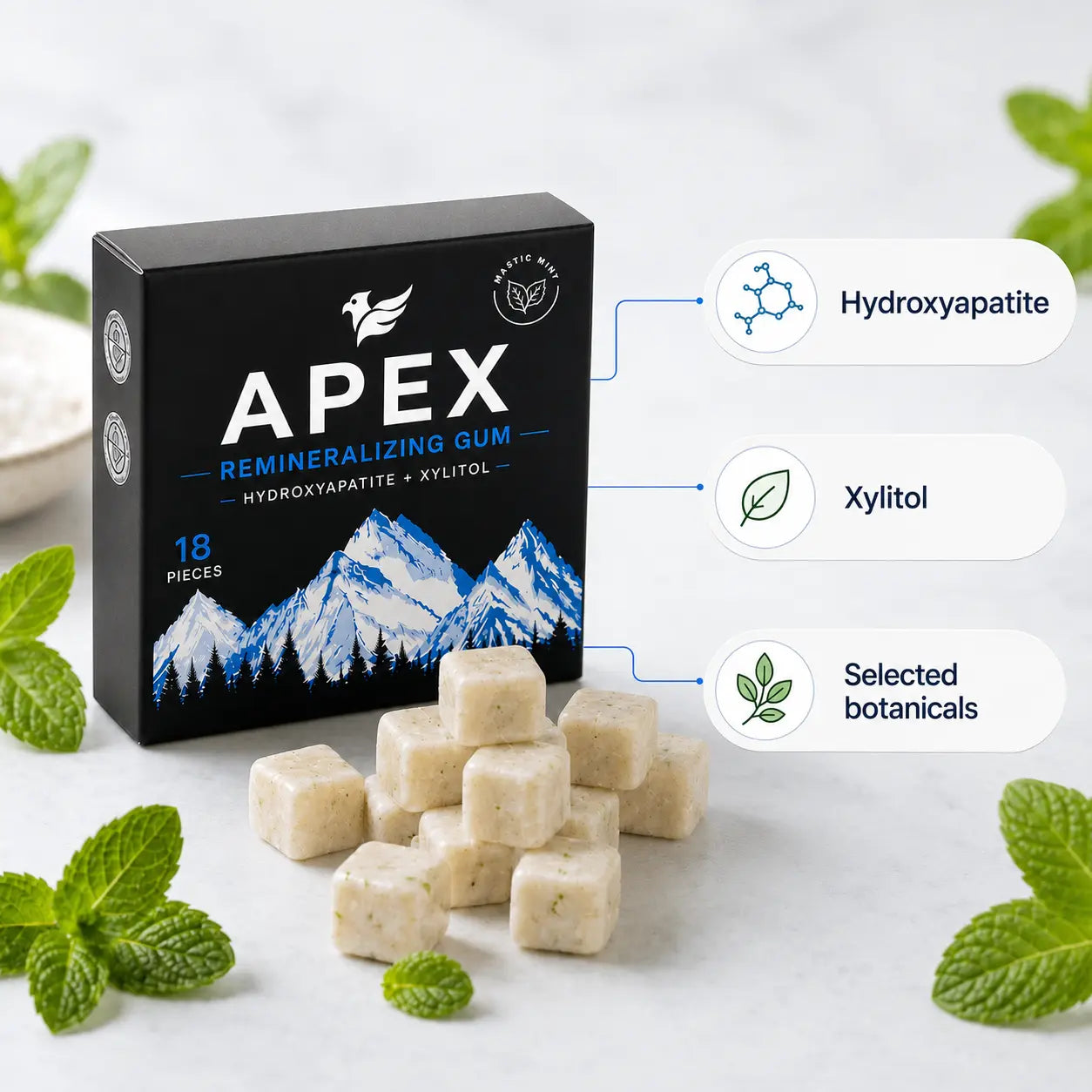 APEX Remineralizing Gum box in black with blue and white mountain graphics, shown with several off-white gum cubes in front on a light marble surface, surrounded by mint leaves. Callouts indicate Hydroxyapatite, Xylitol, and Selected botanicals.