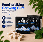 Two black boxes of APEX Remineralizing Gum with several beige chewable cubes in front, shown on a light wood surface with mint leaves and marketing text on a beige background.