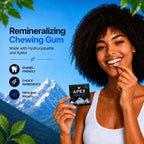 A smiling woman with dark curly hair holds a small black Apex brand chewing gum packet while posing in front of a blue sky and mountain backdrop. Text on the left reads 'Remineralizing Chewing Gum' with bullet points about enamel-friendly ingredients and fresh breath.