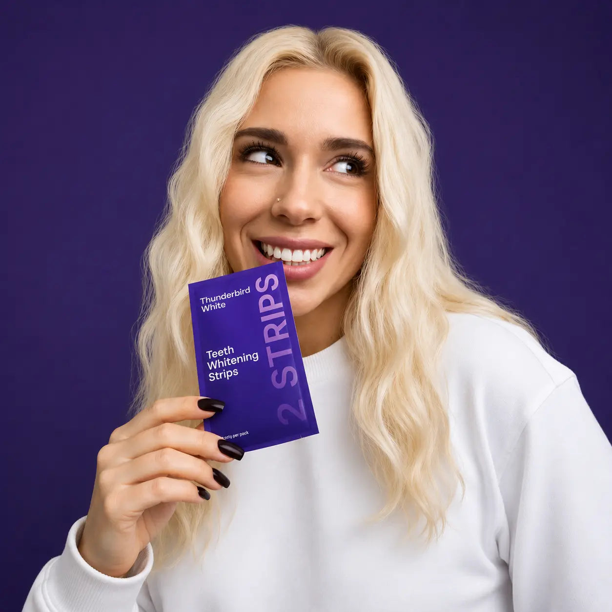 Woman holding a package of teeth whitening strips against a purple background
