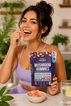 Woman holding a package of mushroom gummies and eating them, with a bowl of gummies and a glass of water on the table.